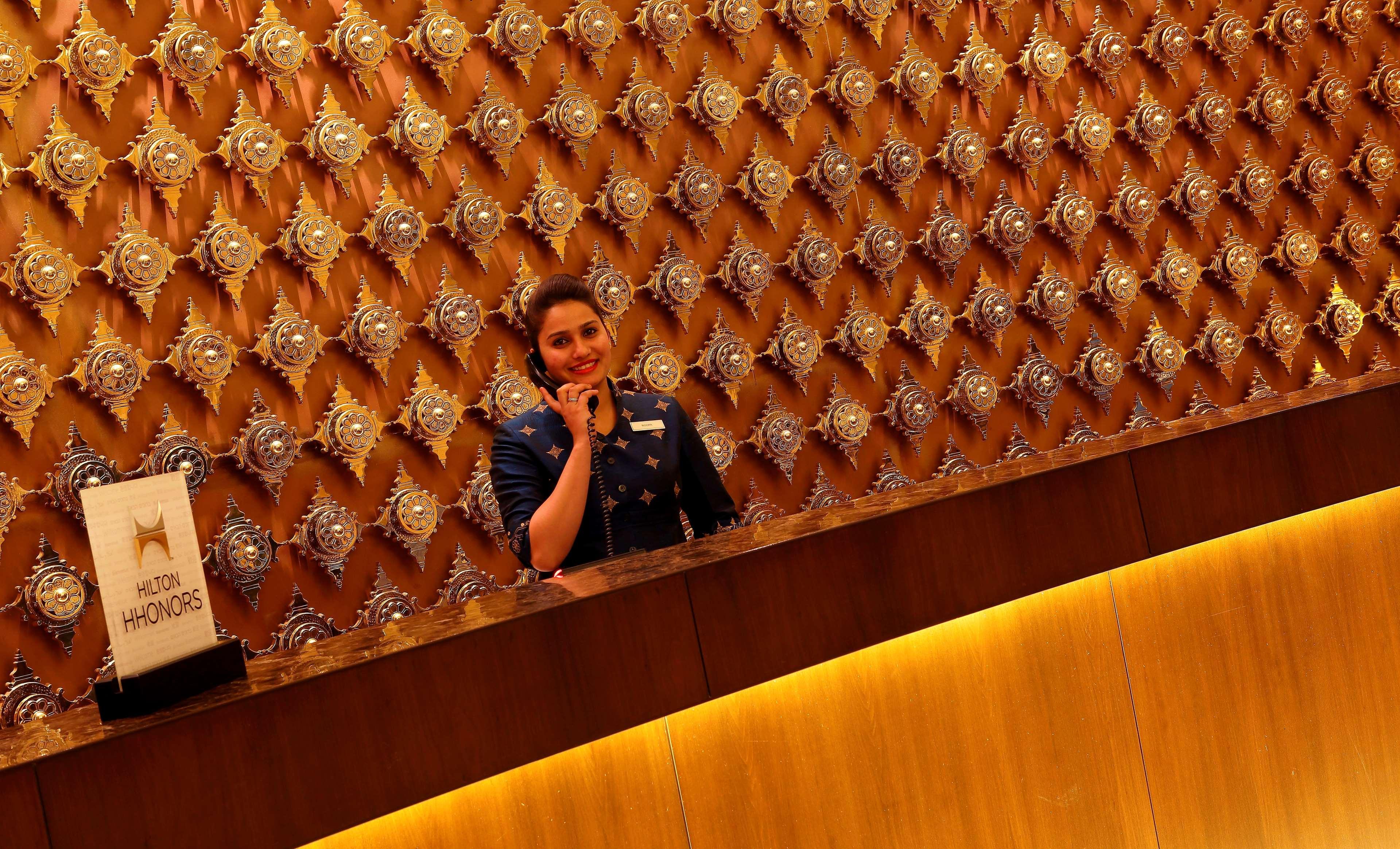 Hilton Jaipur Hotel Buitenkant foto A hotel receptionist at work